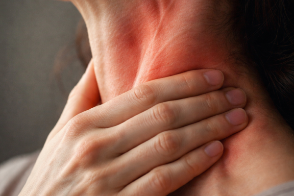 A close-up of a person’s neck and jawline, with visible tension in the muscles and a hand gently massaging the area, symbolizing the "armor" created by anxiety.