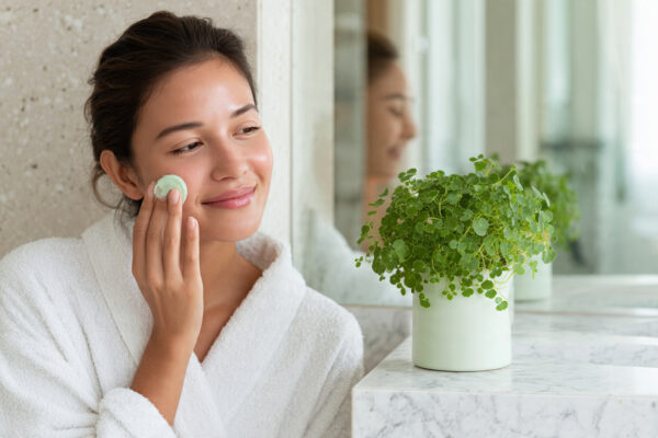 Woman gently applying soothing Centella Asiatica cica cream to calm her face