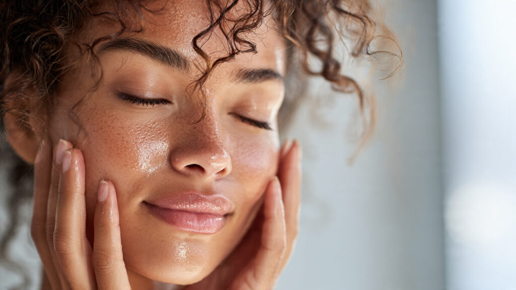 Woman gently patting hyaluronic acid clear serum onto a wet damp glowing face