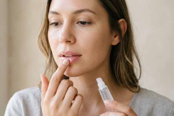 A woman applying soothing lip balm to treat dry and chapped lips.